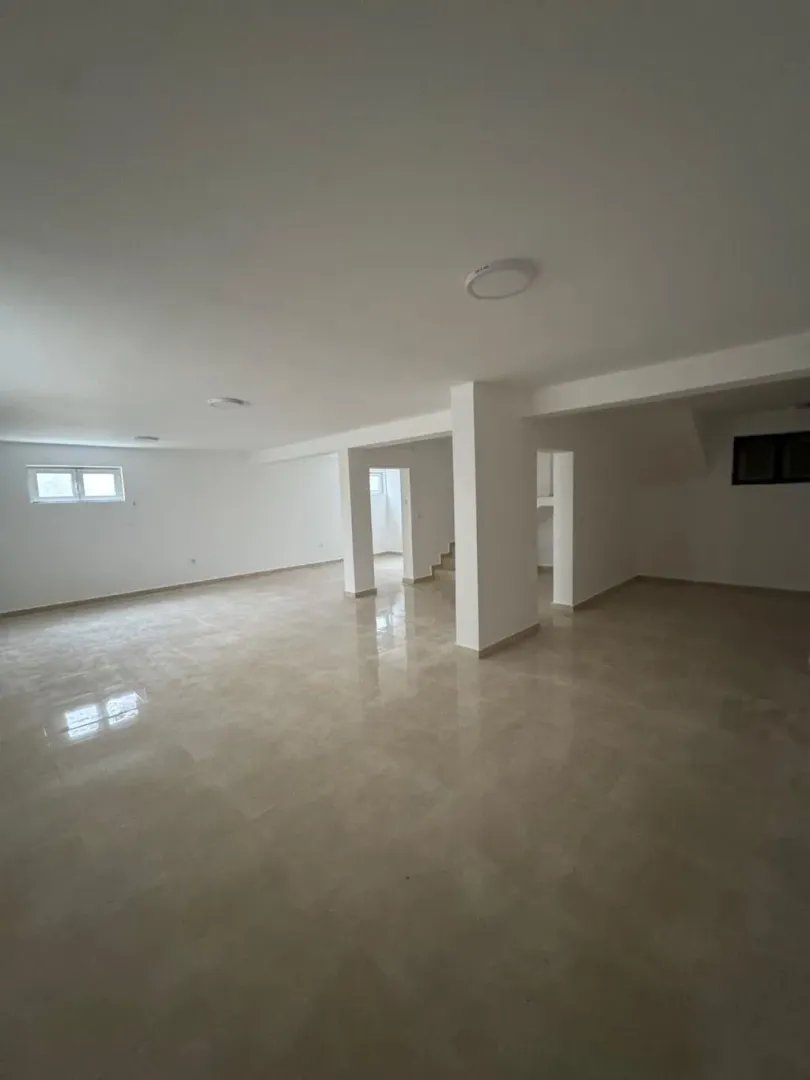 Empty bright room with ceramic floor tiles and support pillars.