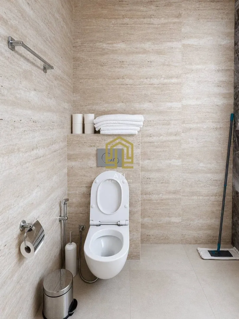 Moderne kupatilo sa WC šoljom i bež pločicama.