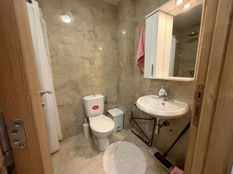Manje kupatilo sa pločicama, wc šoljom, umivaonikom i ogledalom sa ormarićem. - image 4
