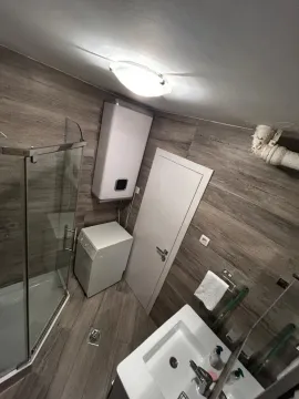 Smaller bathroom with a shower cabin, washbasin, and water heater. - image 2