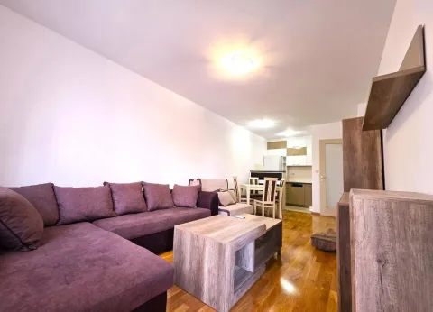 Living room with a sofa, coffee table, and dining area in the background. - image 4