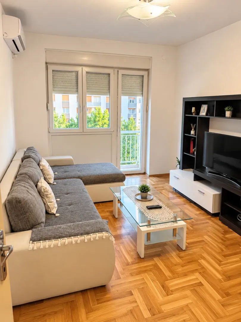 Living room with sofa, TV unit and hardwood flooring.