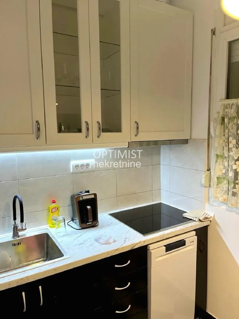 View of a section of the kitchen with a sink, built-in cooktop, and upper cabinets.