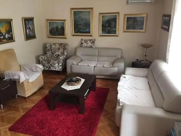 Dnevna soba sa garniturom za sjedenje, klub stolom i crvenim tepihom.