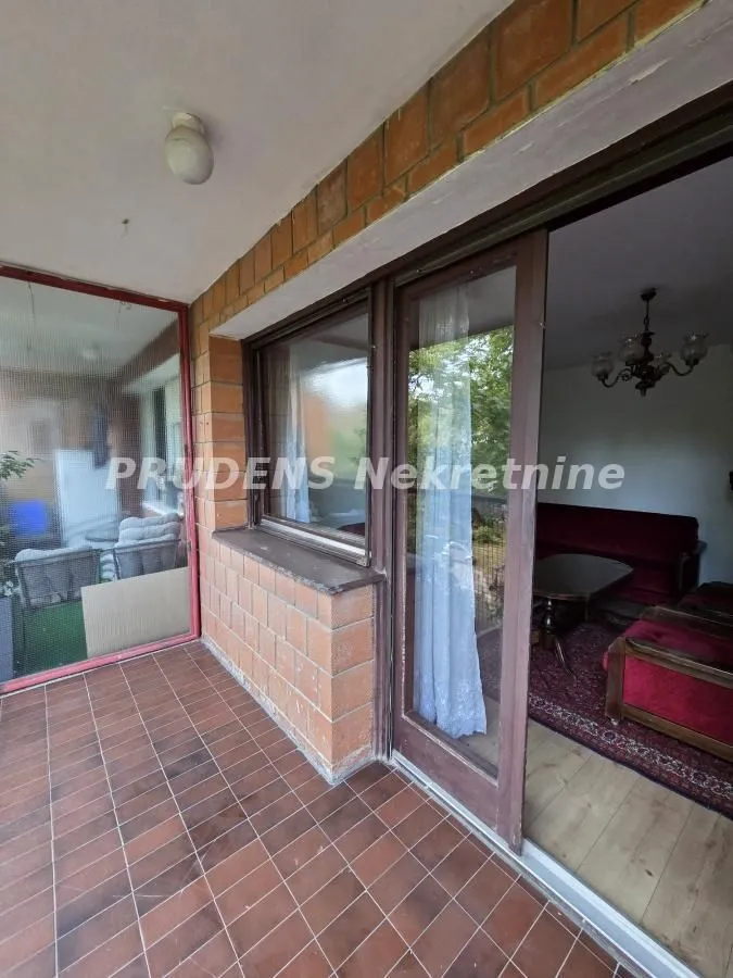 Natkriveni balkon sa popločanim podom i pogledom u unutrašnjost prostorije.