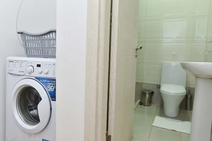 View of the bathroom with a washing machine in the hallway.