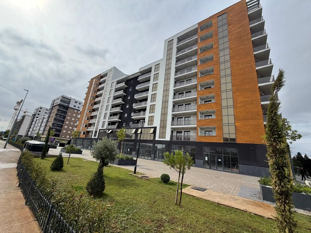 Eksterijer moderne stambene zgrade sa uređenim dvorištem.