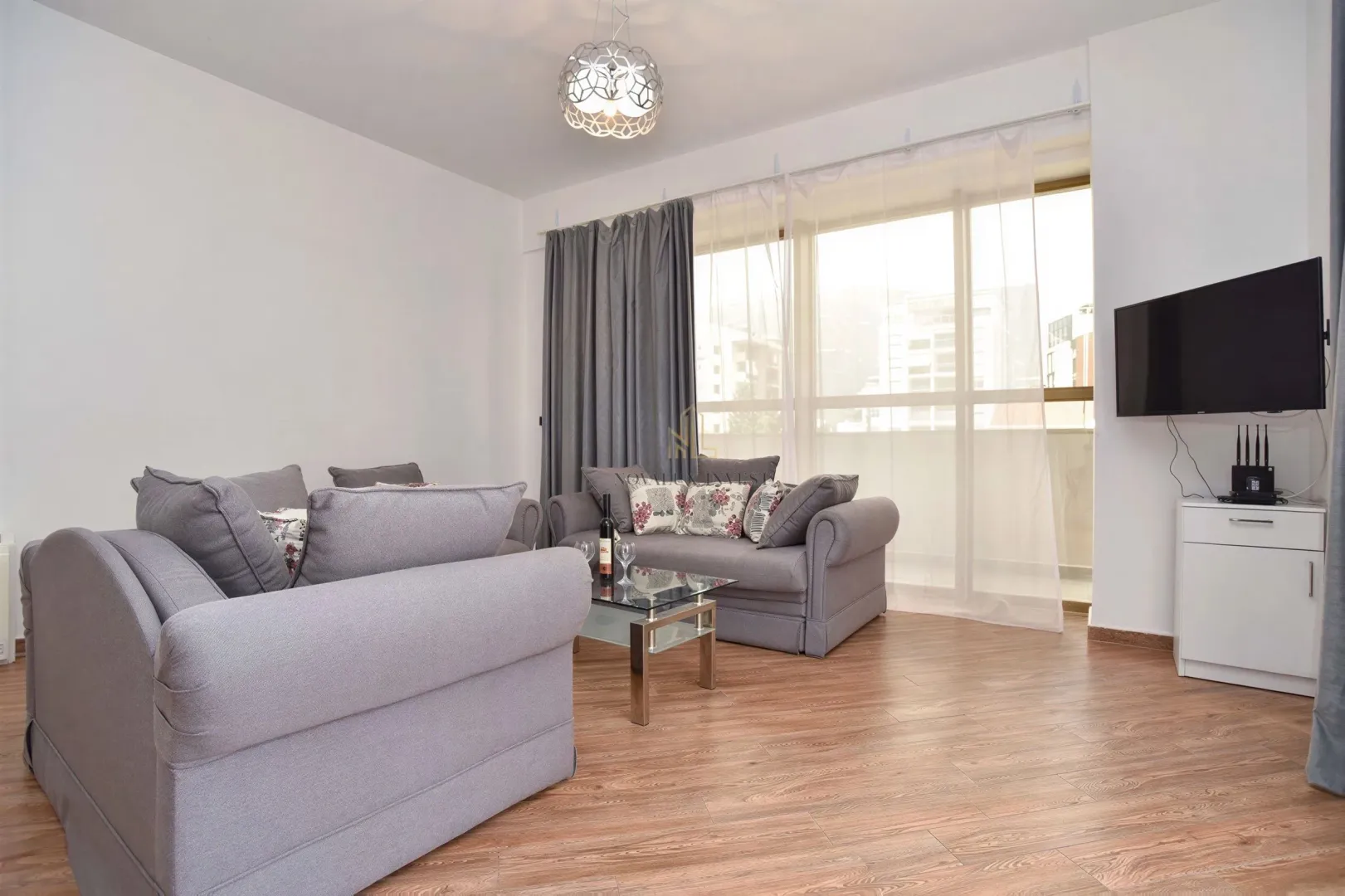 Living room furnished with a grey sofa set, coffee table, and television.