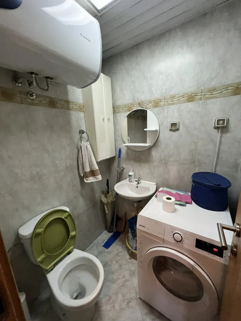 Malo kupatilo sa veš mašinom, lavaboom i toaletom.