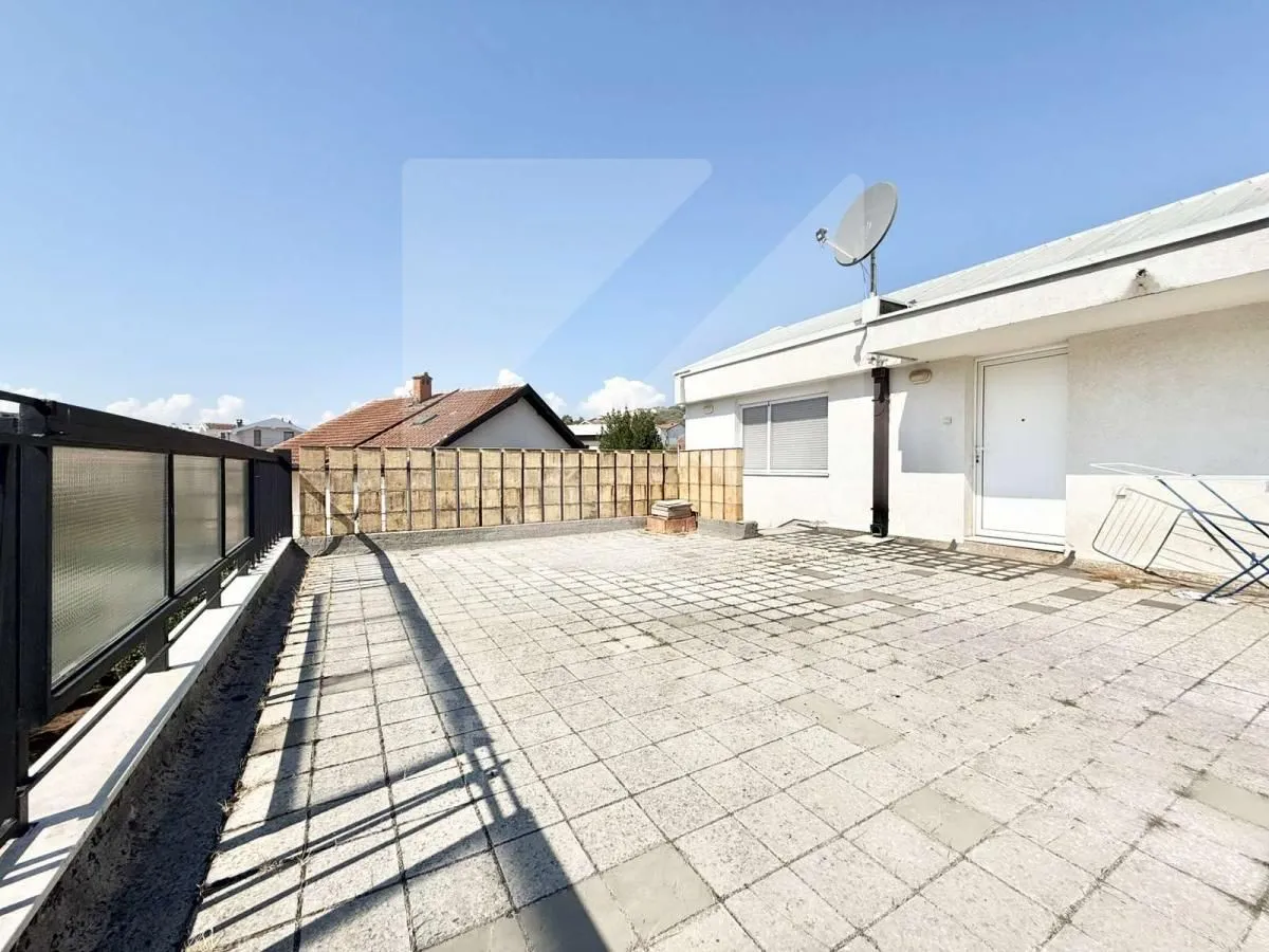 Large tiled terrace with railing and building entrance door.