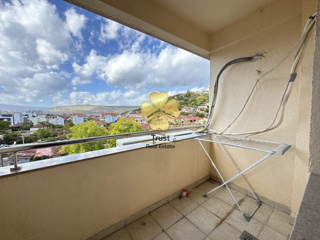 Small covered balcony with a view of the city and surrounding hills.
