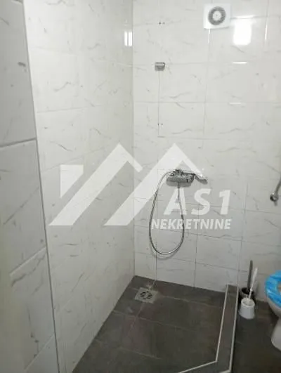View of the walk-in shower and part of the bathroom with white wall tiles.