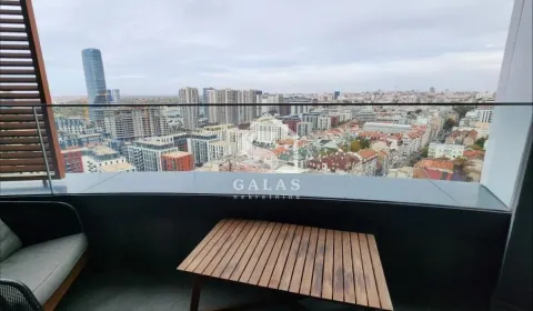 City view from a balcony furnished with a table and an armchair. - image 13