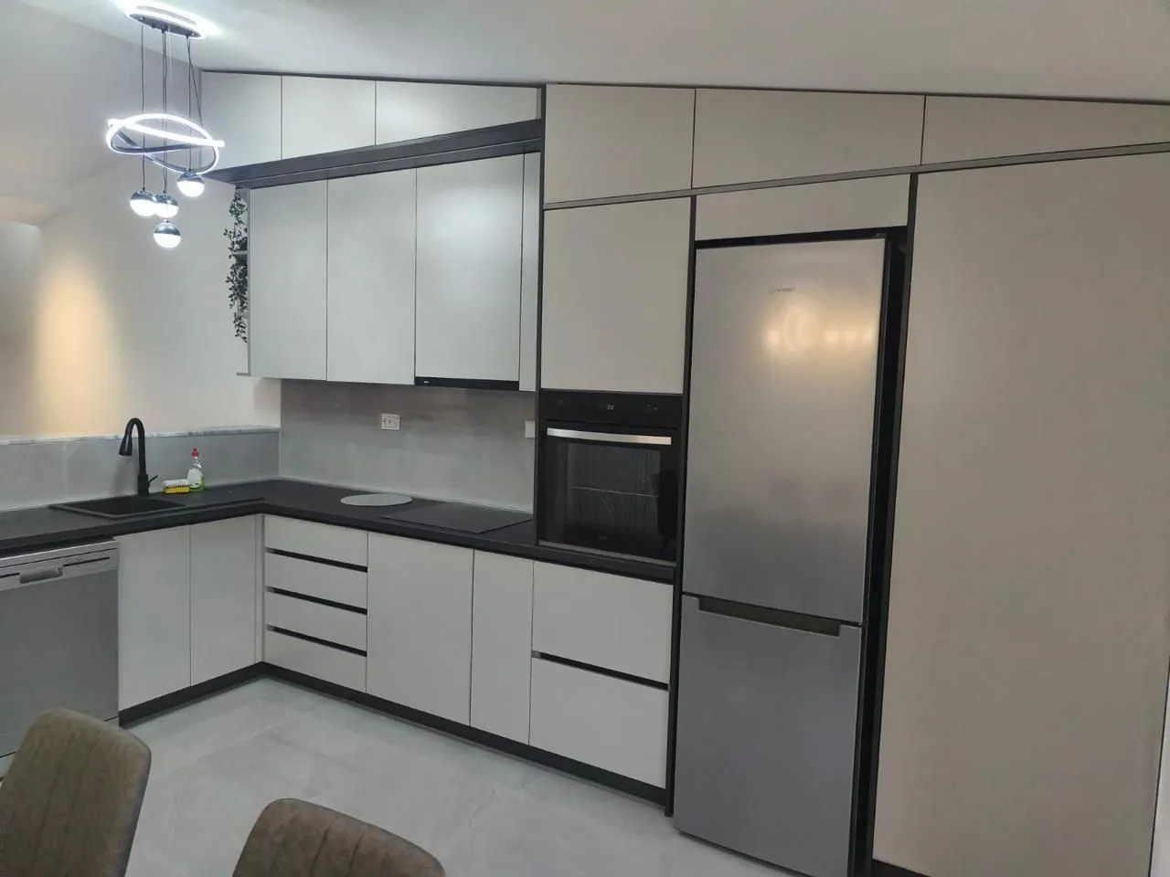 Modern kitchen with white cabinetry, built-in appliances, and a dark countertop.