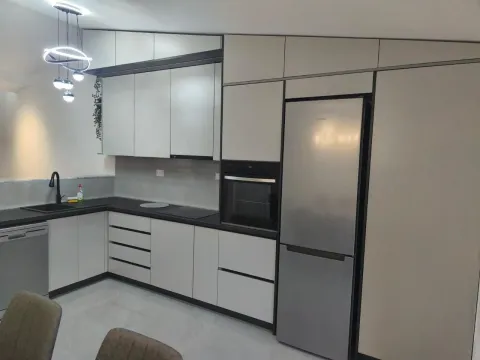 Modern kitchen with white cabinetry, built-in appliances, and a dark countertop. - image 3