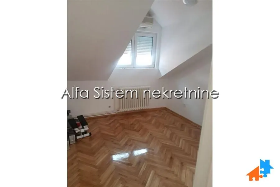 Prazna potkrovna soba sa parketom i kosim plafonom.