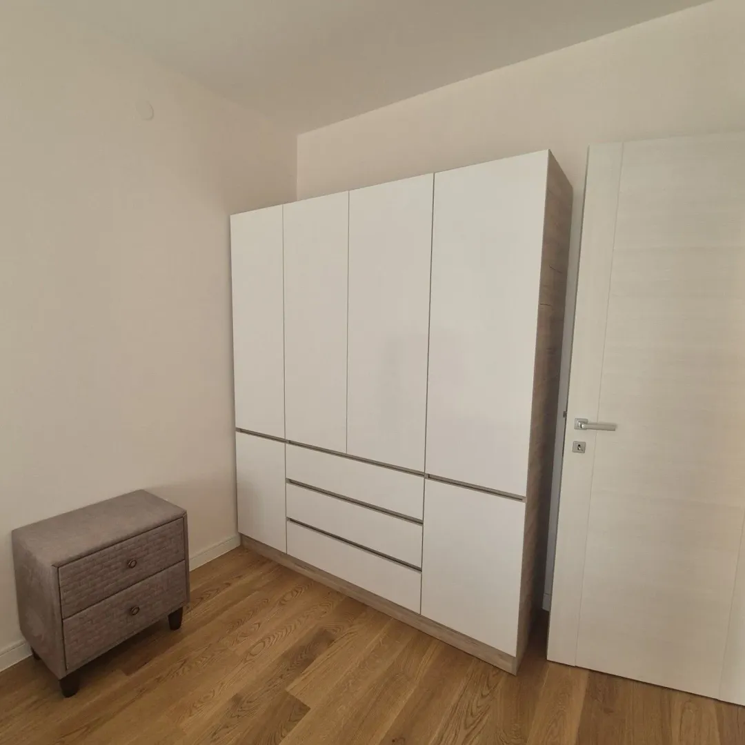 Spavaća soba sa velikim bijelim garderoberom i manjom komodom.