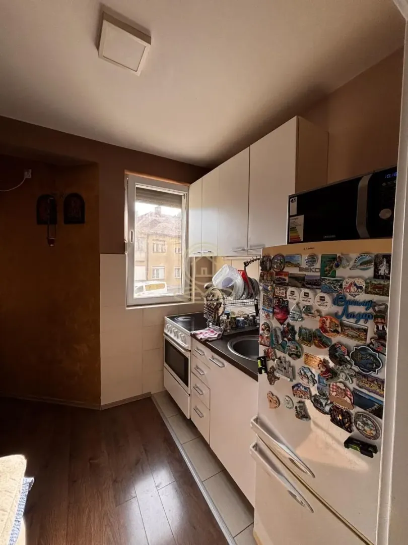 Small kitchen with white cabinets, a refrigerator, and a window.