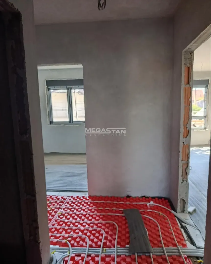 Pogled na unutrašnjost nekretnine u fazi renoviranja sa postavljenim podnim grejanjem.