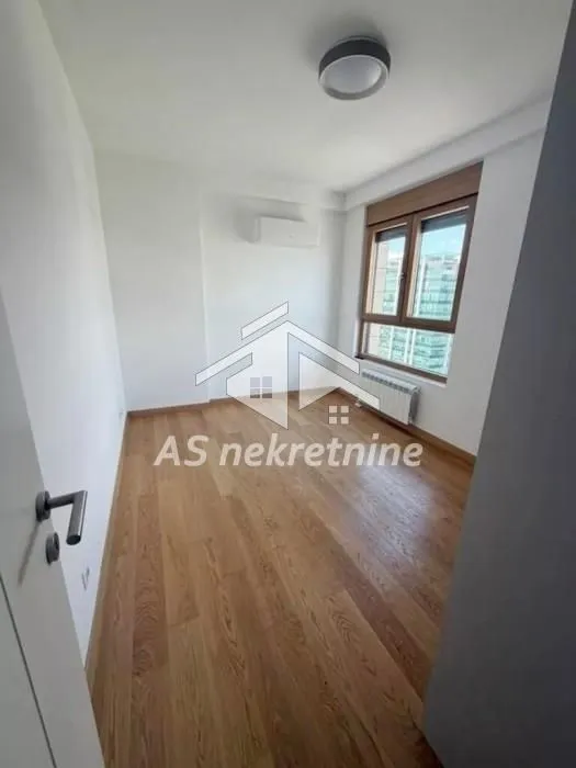 Empty room with wooden flooring, an air conditioning unit, and a window.