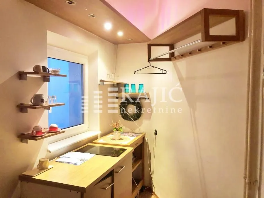 Small kitchen with built-in units and shelves by the window.