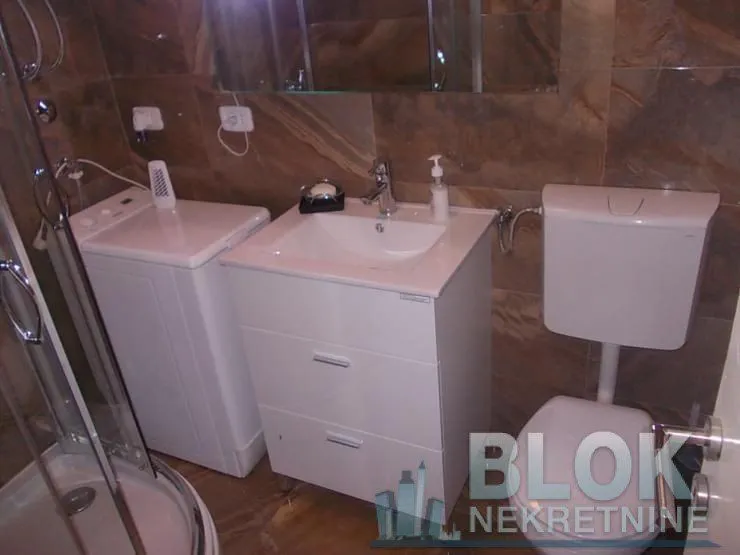 Bathroom equipped with a shower cabin, washbasin, and washing machine.