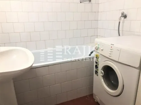 Smaller bathroom with a bathtub, washbasin, and washing machine. - image 9