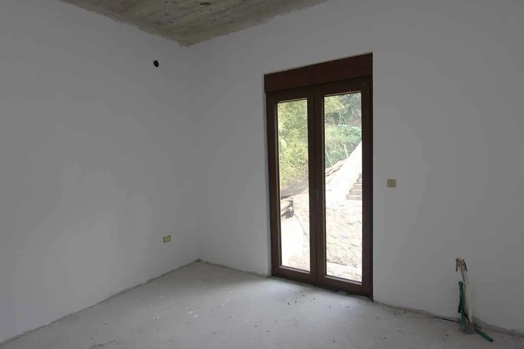 Prazna soba u sivoj fazi sa balkonskim vratima.