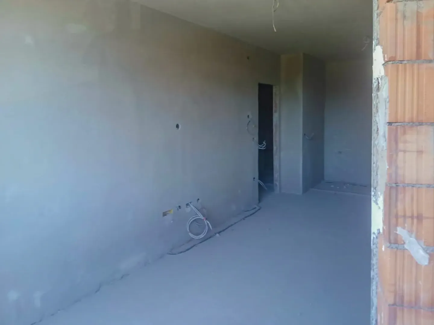 Neopremljena prostorija u izgradnji sa malterisanim zidovima i vidljivim elektroinstalacijama.