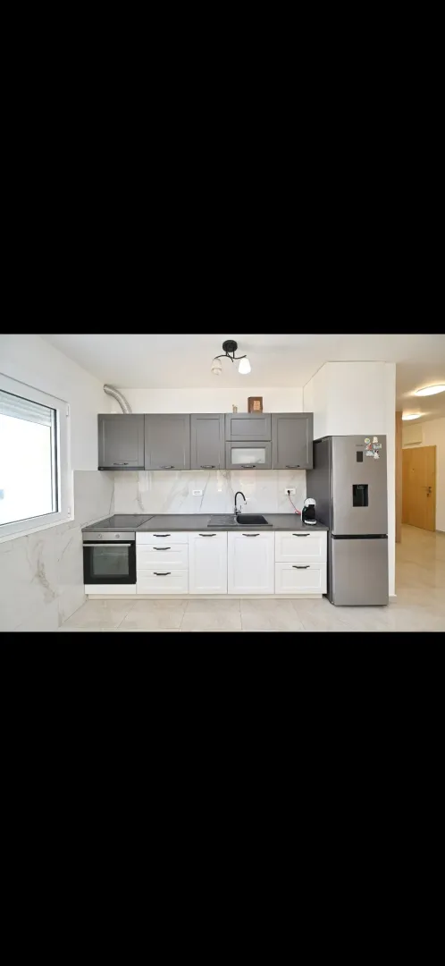 Modern kitchen with grey and white cabinets and built-in appliances.
