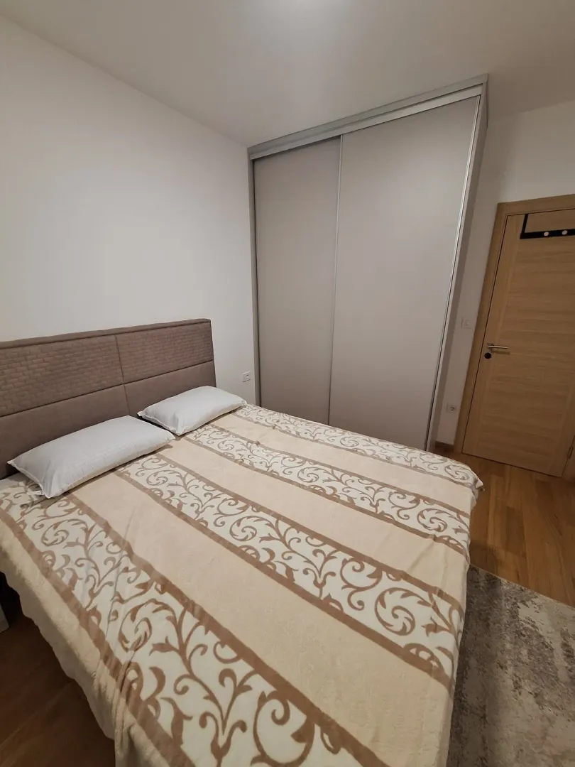 Furnished bedroom with a double bed, wardrobe, and wooden flooring.
