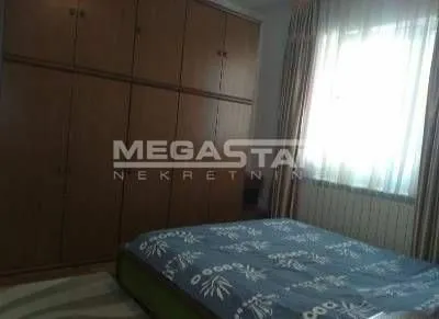 Spavaća soba sa bračnim krevetom i velikim drvenim ormanom. - image 4