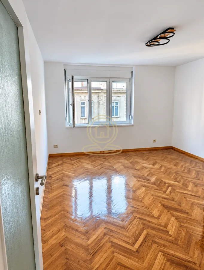 Empty room with parquet flooring and white walls.