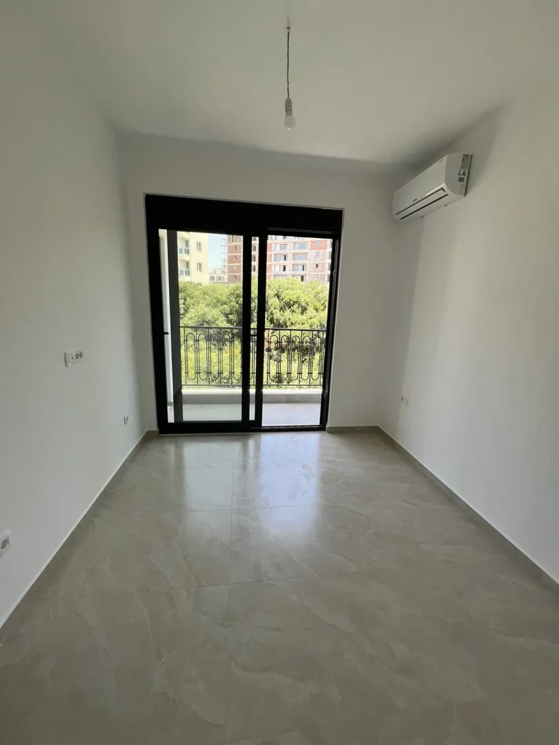 Empty room with access to a balcony and an air conditioning unit.