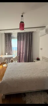 Spavaća soba sa bračnim krevetom, trpezarijskim stolom kod prozora i pogledom na more. - image 7