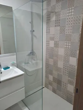 Modern bathroom with a walk-in shower and decorative tiles. - image 3