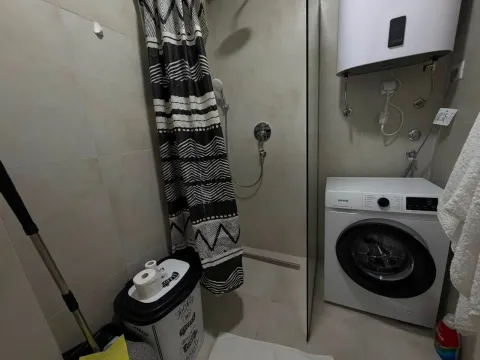 Bathroom with a shower cabin, washing machine, and water heater. - image 13