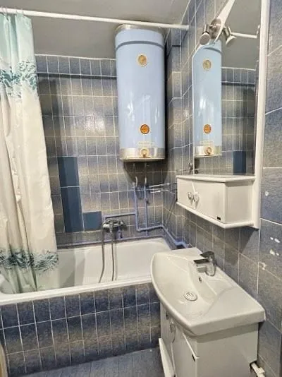 Bathroom with a bathtub, sink, and water heater tiled in blue.