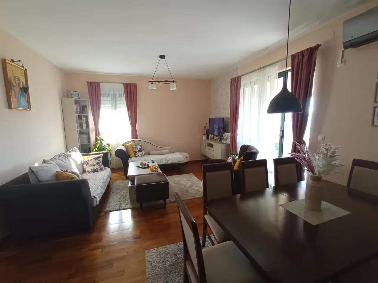 Living room with seating furniture, dining table, and windows.