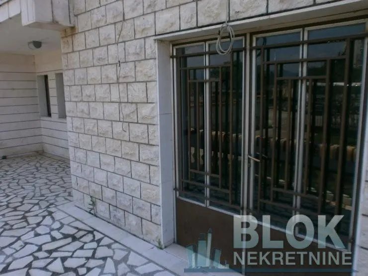Building entrance with a paved courtyard and metal doors.