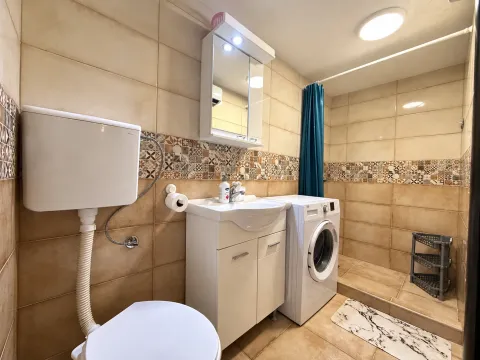 Fully equipped bathroom with a shower cabin, vanity unit, and washing machine. - image 10
