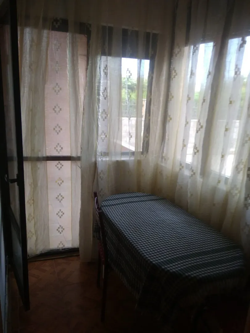 Zastakljeni balkon sa stolom i stolicama pored prozora sa zavjesama.