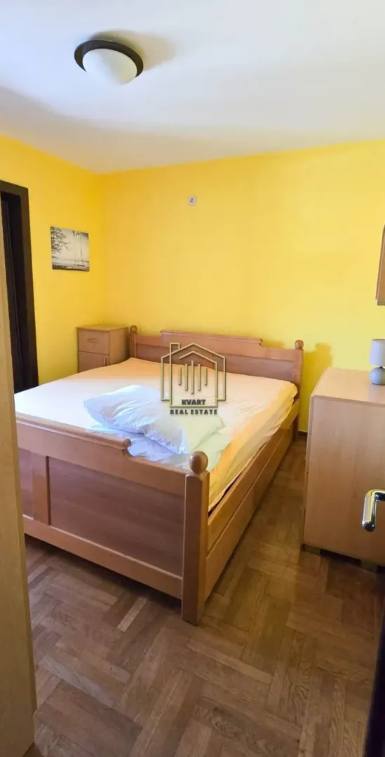 Spavaća soba sa bračnim krevetom i žutim zidovima.