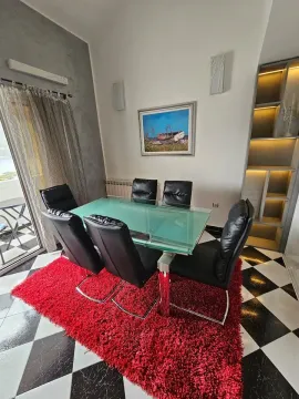 Dining area with a table, black chairs, and a red rug. - image 8