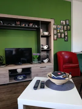 Living room with television, wooden cabinet and a red armchair. - image 4