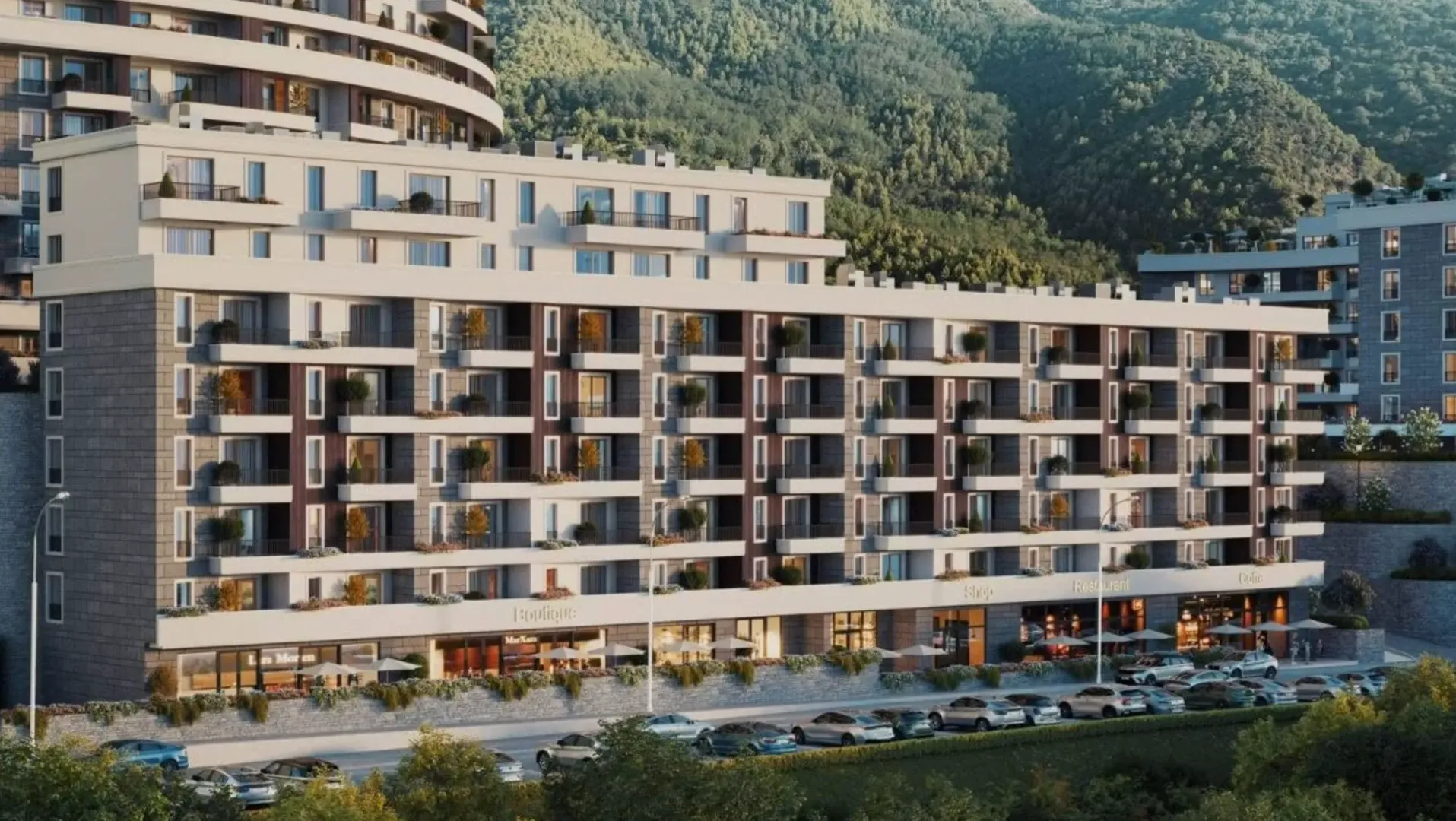 Pogled na spoljašnjost moderne stambene zgrade sa poslovnim prostorima u prizemlju i okolnim zelenilom.