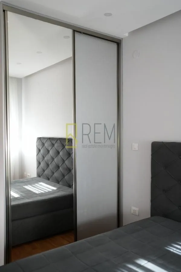 Modern bedroom with a double bed and a mirrored built-in wardrobe.