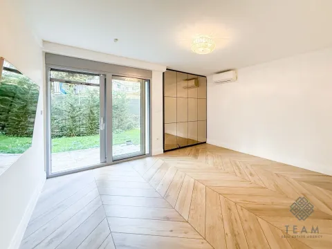 Prazna soba sa drvenim podom, velikim ogledalom i staklenim vratima koja vode u dvorište. - image 10