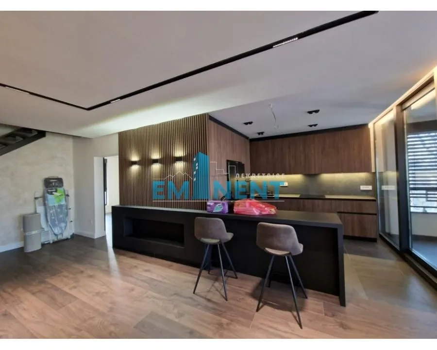 Modern kitchen with a bar counter, wooden wall panels, and built-in units.