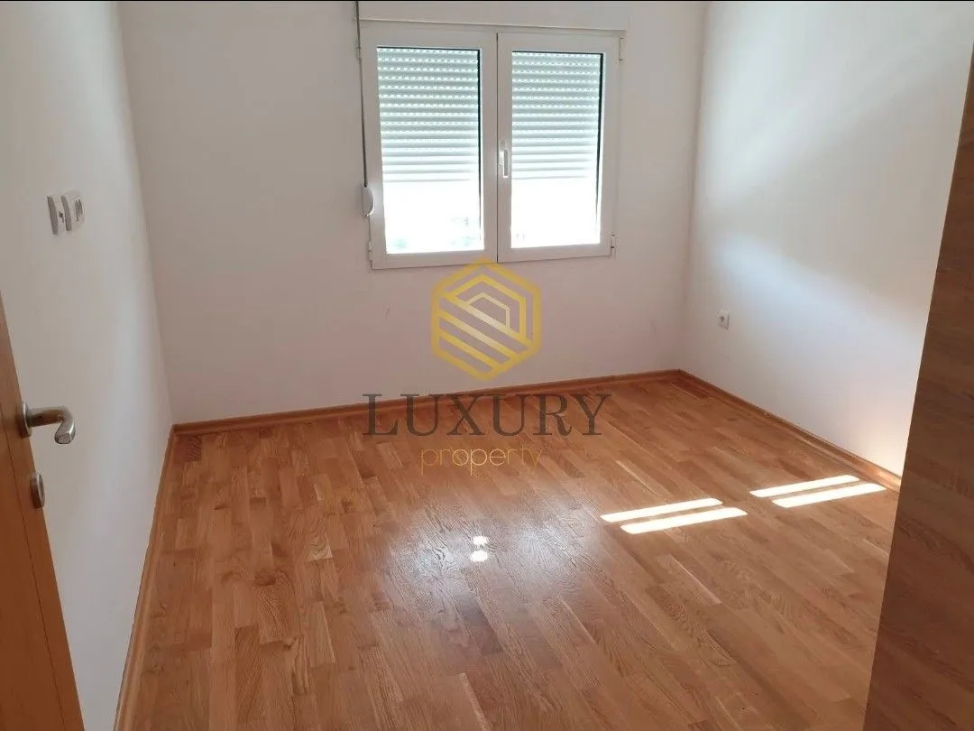 Empty room with hardwood flooring and a window.